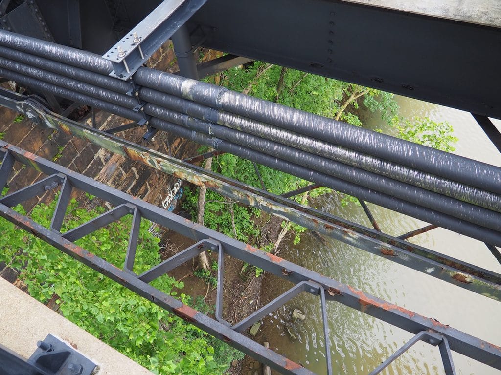 a photo of a river taken from a bridge above, showing graffiti on the bridge's support